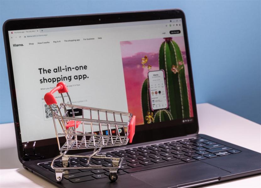 Shopping cart in front of computer screen for Klarna buy now pay later app — Stock Editorial Photography
